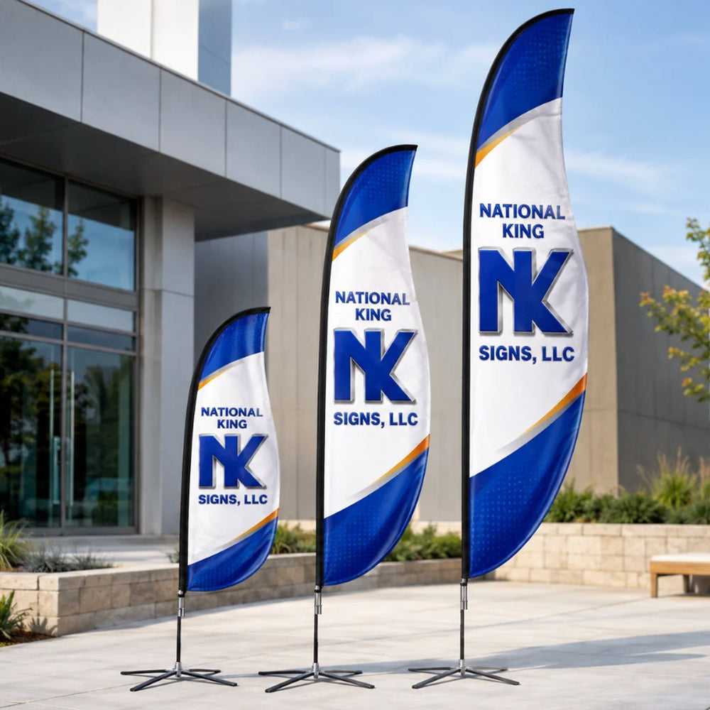 Three Print Solution Plus branded blade flags in different heights, with blue, white and gold graphics and black cross bases outside a modern building.